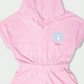 Flat lay of pink girls cotton romper with hood and elastic waist